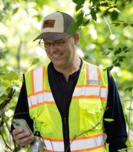 Photo of Kelly, who visits five to seven sites a year, hiking the property and taking GPS-located photos.