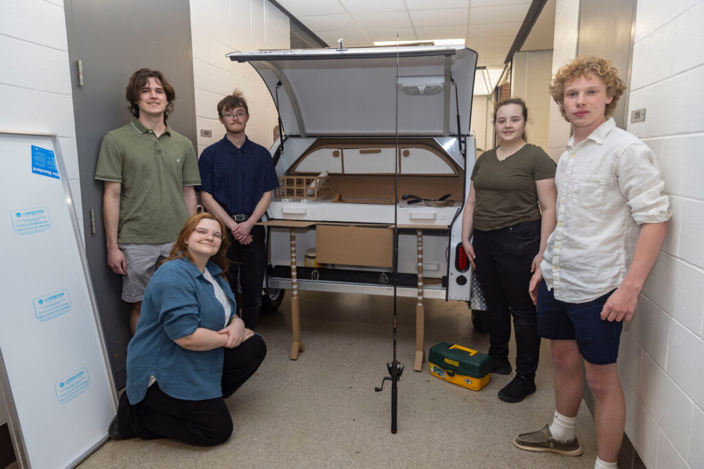 Photo of Mackenzie Bruesewitz, Charlie Kalas, Darik Moilien, Lauren Mescher and Britton Bernhard presenting their Camp-Inn Road Toad kitchenette mockup. / UW-Stout
